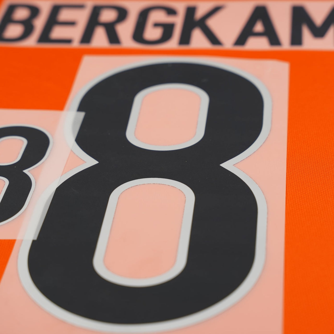 Reproduction Netherlands football name set in orange, player lettering and numbering laid flat, ready for heat-press application.